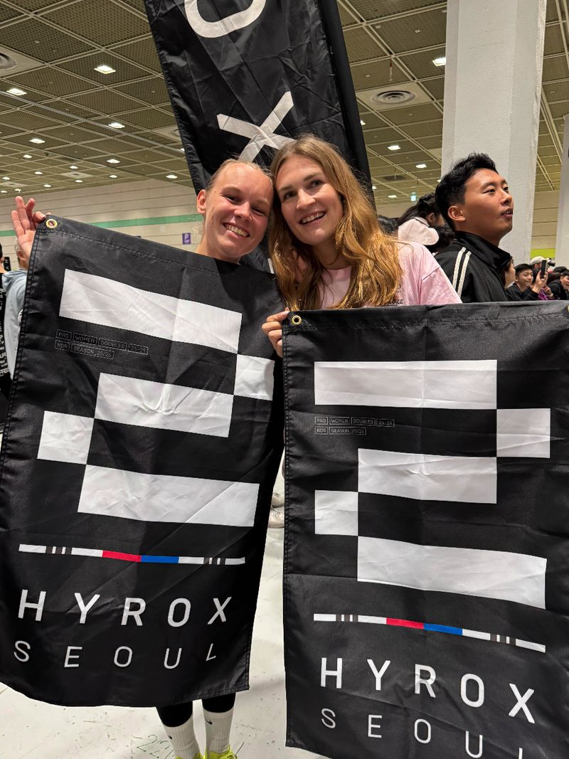 Twee atleten van Momentom met de Hyrox Seoul vlaggen