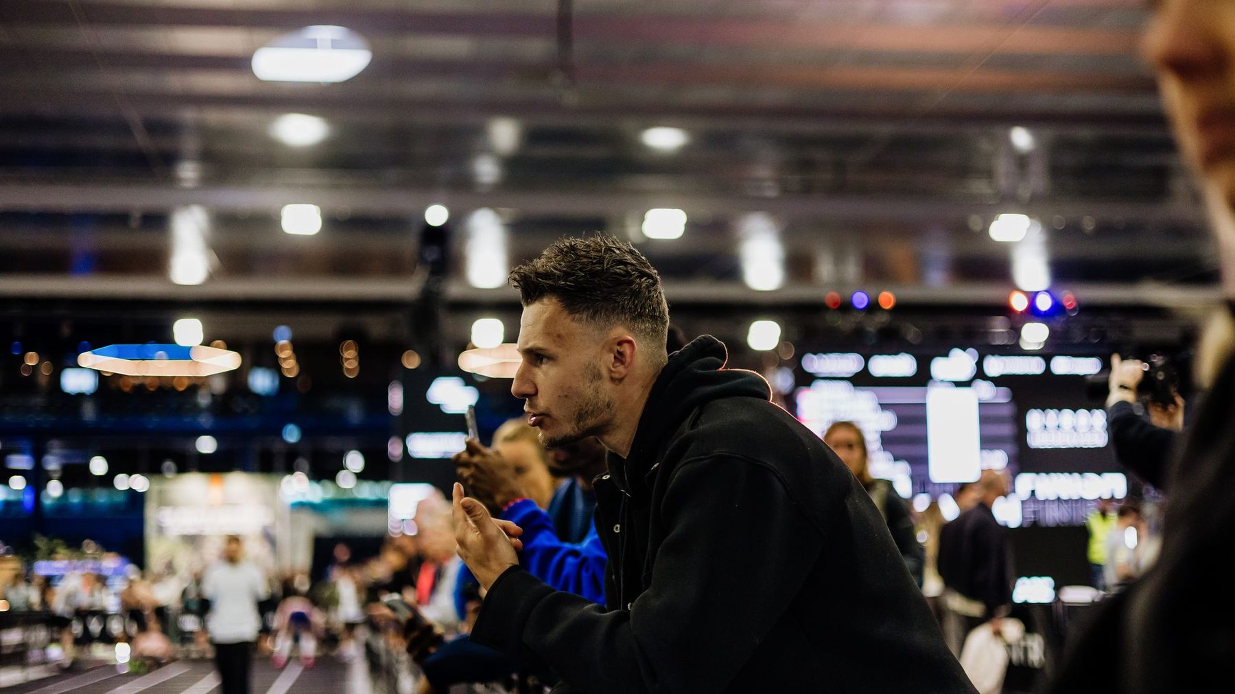 Thomas de Rover kijkt geconcentreerd toe vanaf de reling terwijl zijn atleet de baan op gaat