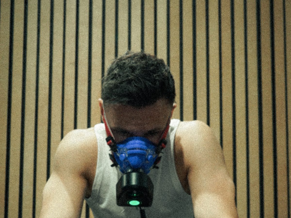Atleet met ademmasker op de roeier tijdens een VO2max-test, met de tijd op de klok erboven